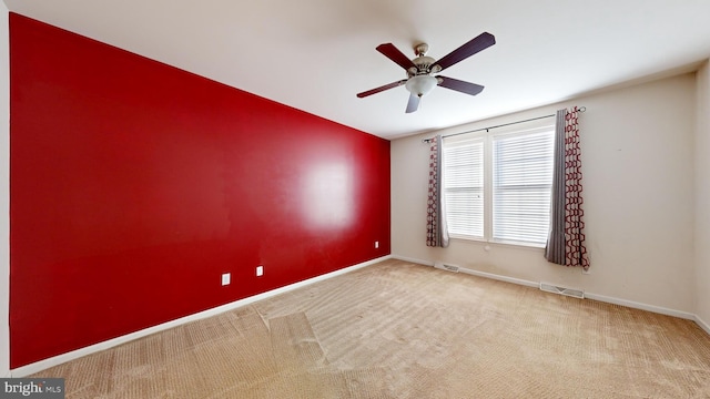 carpeted spare room featuring visible vents, ceiling fan, and baseboards