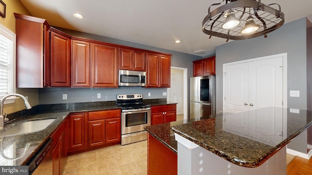 kitchen featuring recessed lighting, a kitchen island, a sink, dark brown cabinets, and appliances with stainless steel finishes