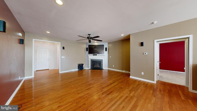 unfurnished living room featuring a ceiling fan, a glass covered fireplace, light wood finished floors, and recessed lighting