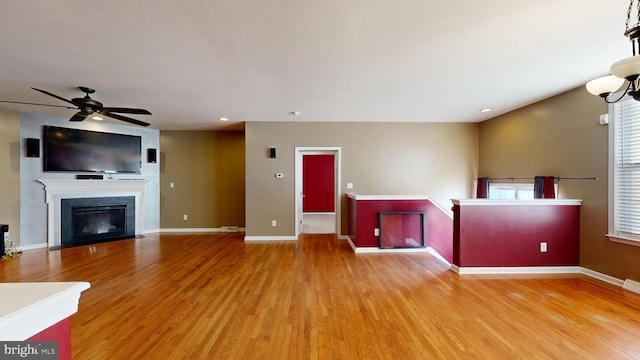 unfurnished living room with light wood-type flooring, a fireplace with flush hearth, baseboards, and recessed lighting