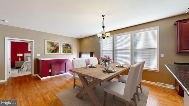 dining area featuring light wood-type flooring, visible vents, baseboards, and an inviting chandelier