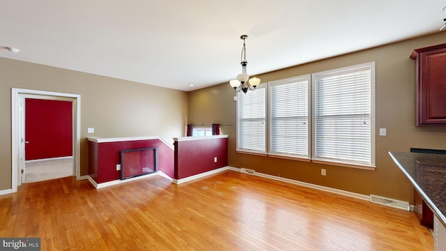 interior space featuring an inviting chandelier, light wood-style flooring, visible vents, and baseboards