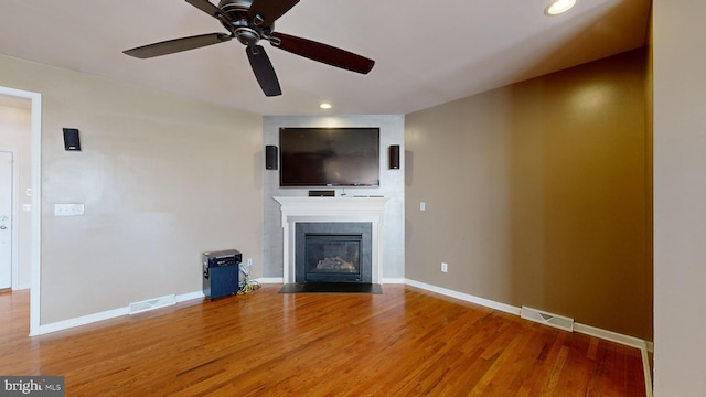 unfurnished living room featuring a fireplace with flush hearth, visible vents, baseboards, and wood finished floors