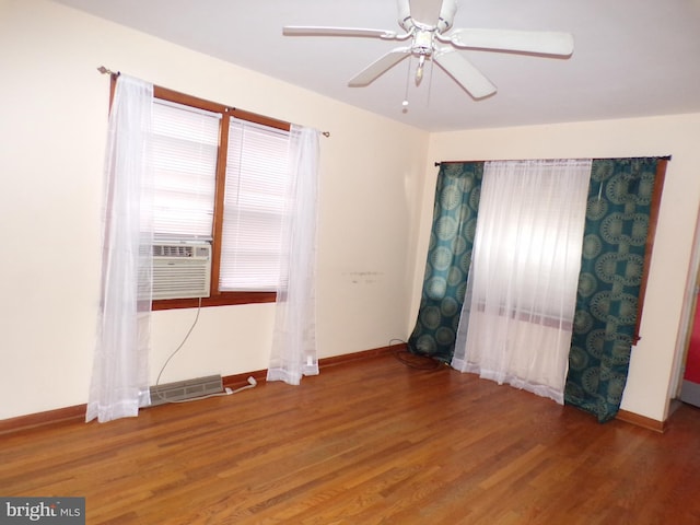 unfurnished room with cooling unit, a ceiling fan, baseboards, and wood finished floors