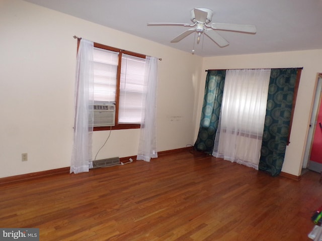 unfurnished room featuring cooling unit, baseboards, and wood finished floors