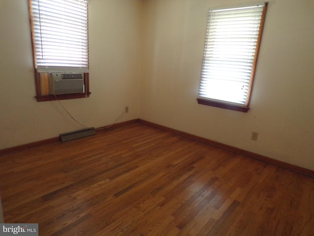 unfurnished room with cooling unit, wood finished floors, visible vents, and baseboards