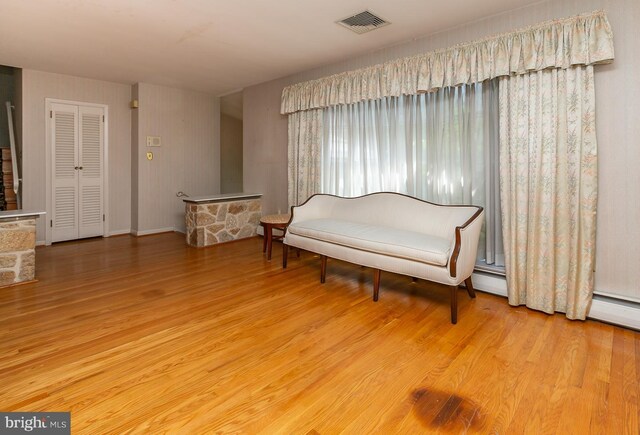 sitting room with a baseboard heating unit and light hardwood / wood-style floors