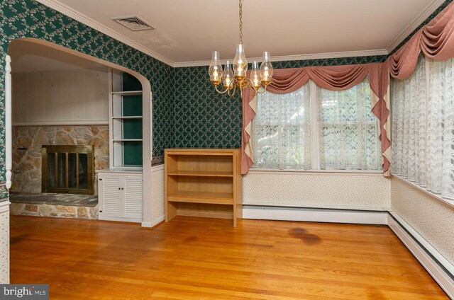 unfurnished dining area featuring a baseboard radiator, a stone fireplace, wood-type flooring, ornamental molding, and a chandelier