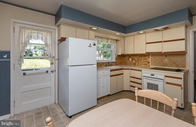 kitchen with sink, light tile patterned floors, white appliances, and decorative backsplash