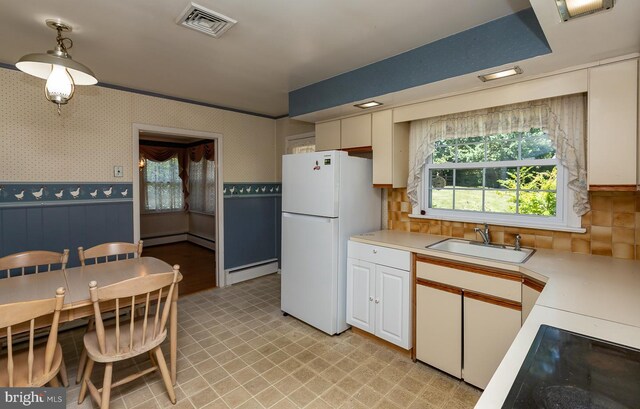 kitchen with white refrigerator, baseboard heating, cooktop, and sink