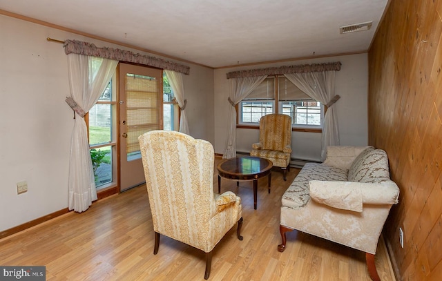 sitting room with baseboard heating, light hardwood / wood-style floors, and crown molding