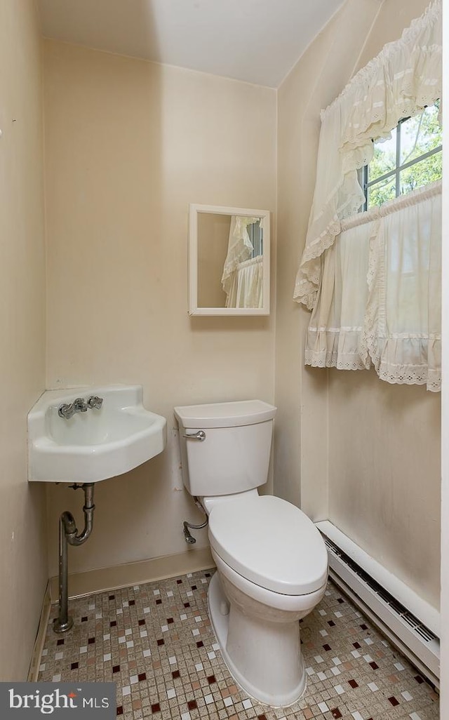 bathroom featuring a baseboard heating unit, toilet, sink, and tile patterned flooring