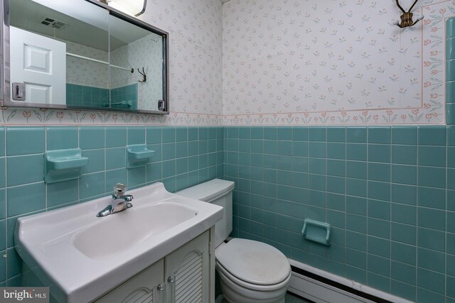 bathroom with vanity, tile walls, toilet, decorative backsplash, and baseboard heating