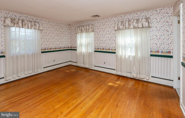 empty room with a healthy amount of sunlight and hardwood / wood-style floors