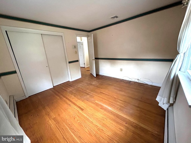 unfurnished bedroom featuring a closet, wood-type flooring, and crown molding