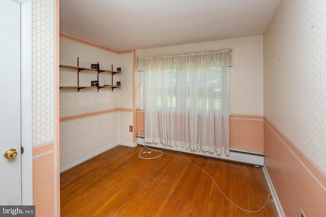 spare room featuring baseboard heating and hardwood / wood-style floors