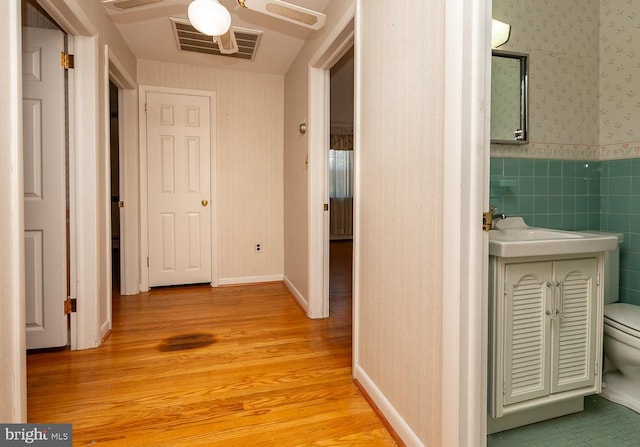 hallway featuring tile walls and light hardwood / wood-style floors