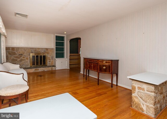 living room with light hardwood / wood-style flooring, wood walls, and a fireplace