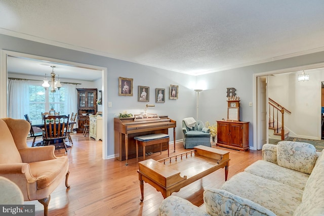 living room featuring a notable chandelier, light wood-type flooring, crown molding, and a textured ceiling