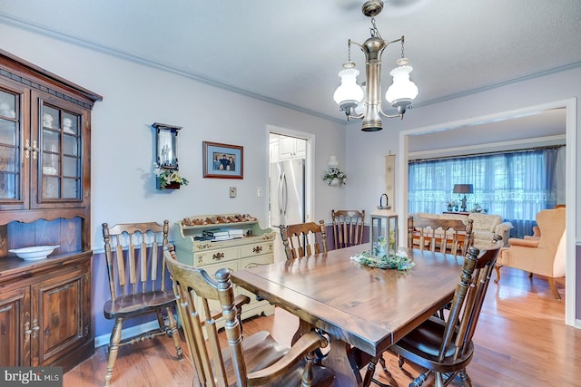 dining area featuring a textured ceiling, crown molding, an inviting chandelier, and light hardwood / wood-style flooring