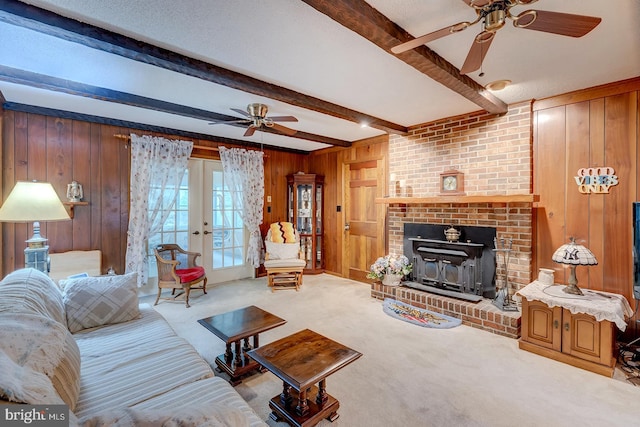 living room with a fireplace, wood walls, beamed ceiling, ceiling fan, and light carpet