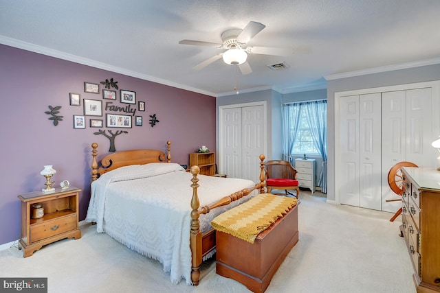 bedroom with ceiling fan, multiple closets, crown molding, and light carpet