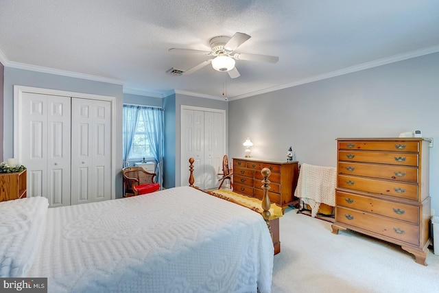 carpeted bedroom featuring a textured ceiling, ornamental molding, two closets, and ceiling fan