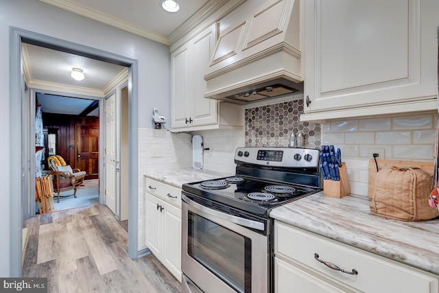 kitchen featuring light stone counters, stainless steel range with electric stovetop, light wood-type flooring, and white cabinetry