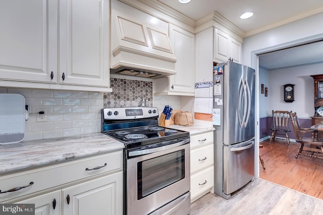 kitchen with light stone counters, light hardwood / wood-style floors, tasteful backsplash, white cabinets, and appliances with stainless steel finishes