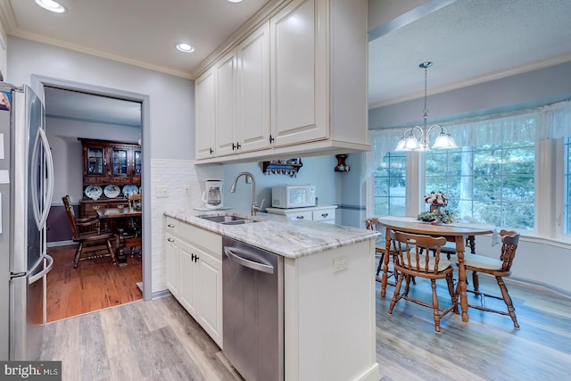 kitchen with sink, white cabinetry, appliances with stainless steel finishes, an inviting chandelier, and light wood-type flooring