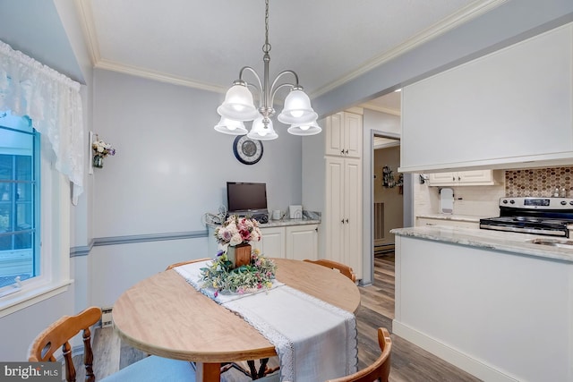 dining area with wood-type flooring, an inviting chandelier, and ornamental molding