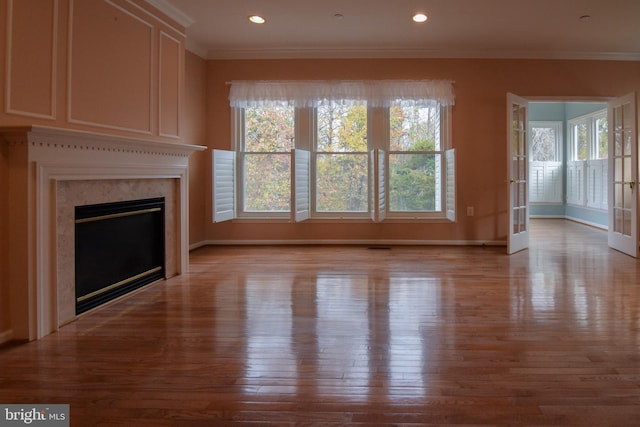 unfurnished living room featuring a high end fireplace, light hardwood / wood-style flooring, and crown molding