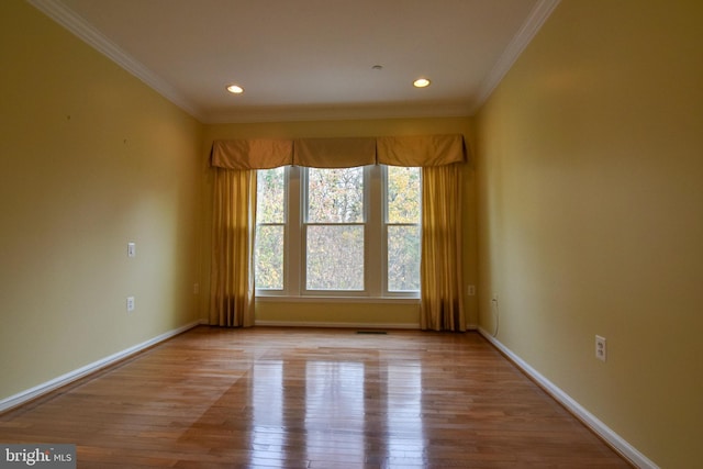 empty room with crown molding and light hardwood / wood-style flooring