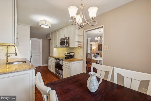 kitchen with a notable chandelier, stainless steel appliances, light stone counters, sink, and decorative backsplash