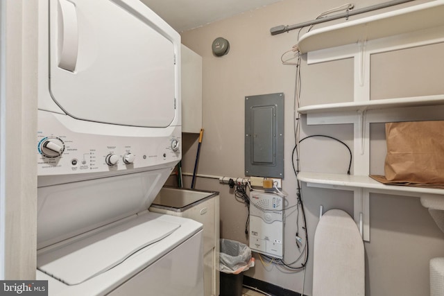 laundry area featuring electric panel and stacked washer / dryer