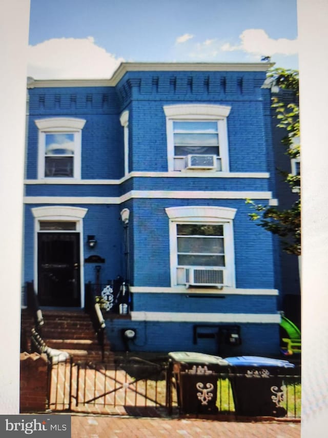 view of front of property with a fenced front yard, cooling unit, brick siding, and entry steps