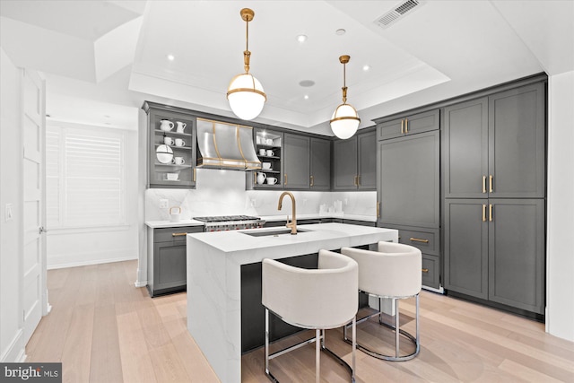 kitchen featuring premium range hood, sink, gray cabinets, and a raised ceiling