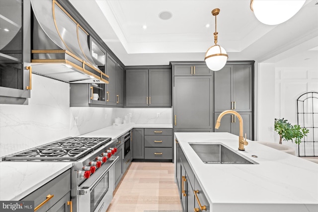 kitchen featuring a raised ceiling, hanging light fixtures, sink, tasteful backsplash, and high end stove