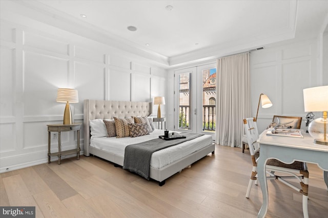 bedroom with ornamental molding, light hardwood / wood-style floors, and a raised ceiling