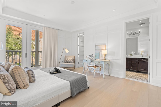 bedroom with sink, light hardwood / wood-style flooring, a notable chandelier, ensuite bath, and access to exterior