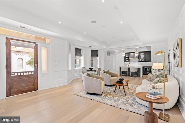 living room with a tray ceiling and light hardwood / wood-style flooring