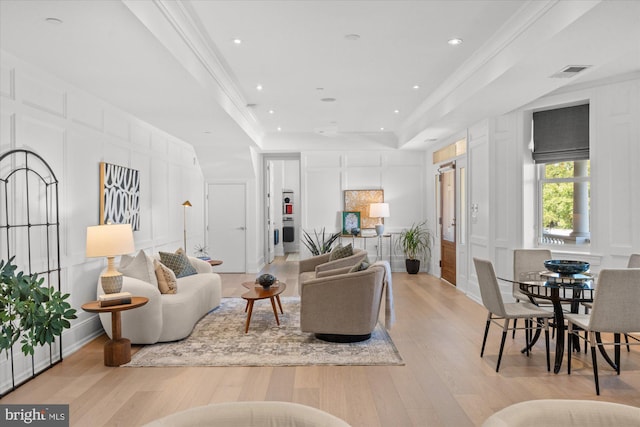 living room with light hardwood / wood-style flooring, crown molding, and a tray ceiling