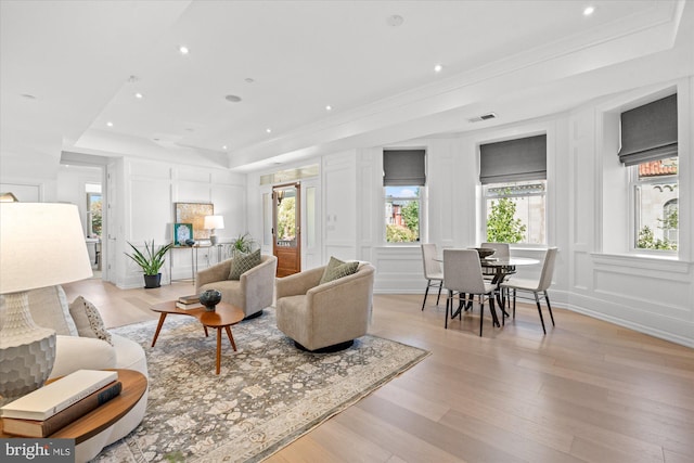 living room featuring ornamental molding, light hardwood / wood-style floors, and a raised ceiling