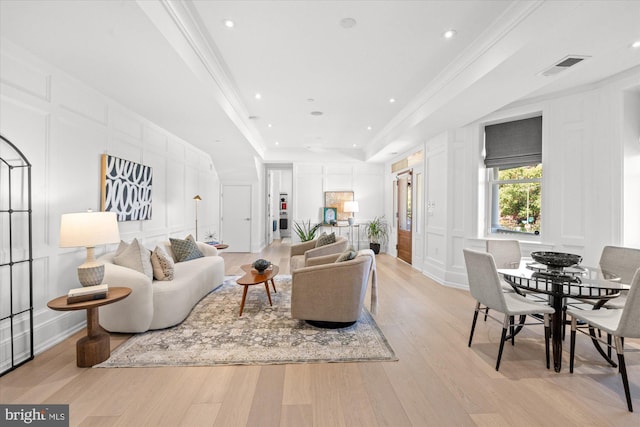 living room featuring light hardwood / wood-style flooring, a tray ceiling, and crown molding