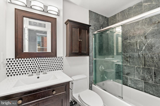 full bathroom featuring bath / shower combo with glass door, vanity, tile walls, and toilet