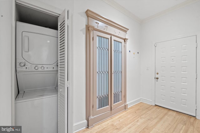 laundry area featuring stacked washer / dryer, light hardwood / wood-style floors, and crown molding