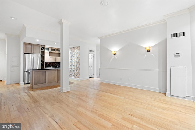 unfurnished living room with light hardwood / wood-style flooring, crown molding, and ornate columns