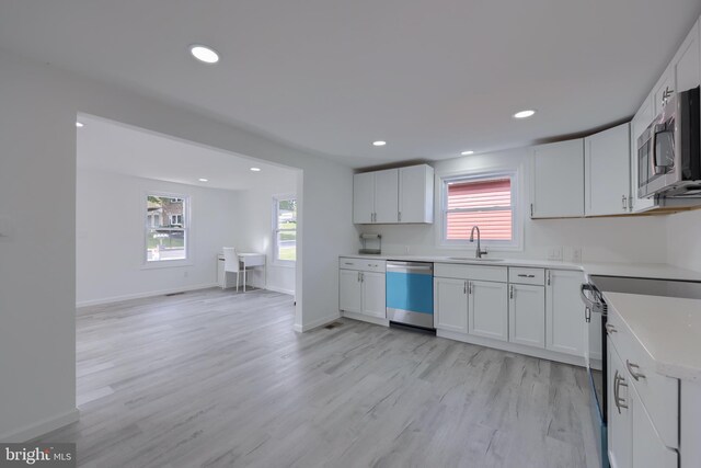 kitchen featuring white cabinets, appliances with stainless steel finishes, light wood-type flooring, and sink