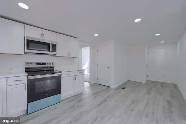 kitchen with white cabinets, appliances with stainless steel finishes, and light wood-type flooring