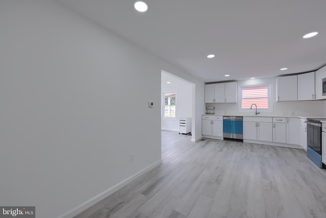 kitchen with white cabinets, appliances with stainless steel finishes, light wood-type flooring, and sink